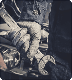 Gros plan sur la main gantée d'un mécanicien tenant une clé au-dessus d'une moto