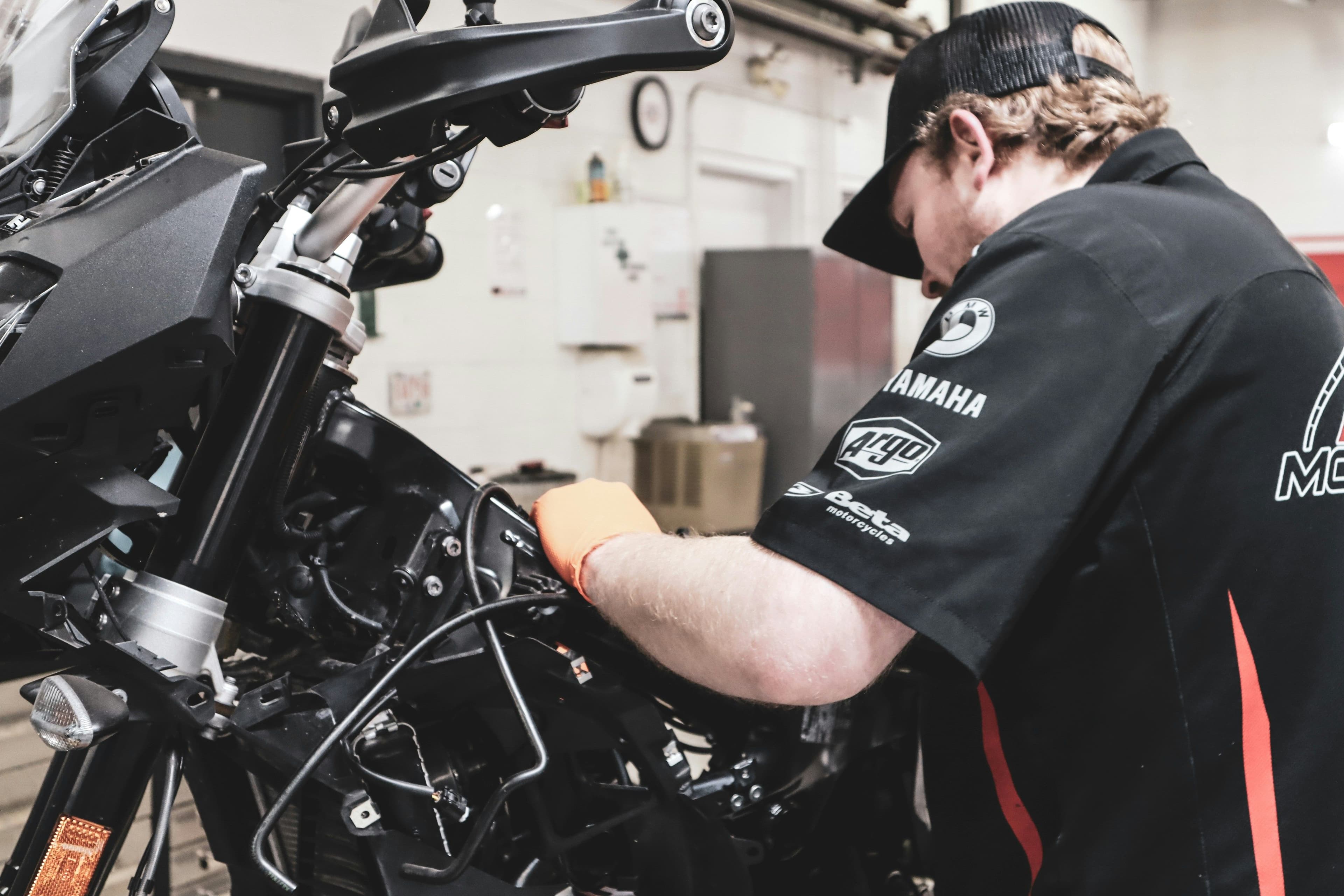 Mécanicien travaillant sur une moto dans un atelier à l’aide du logiciel Carsu.