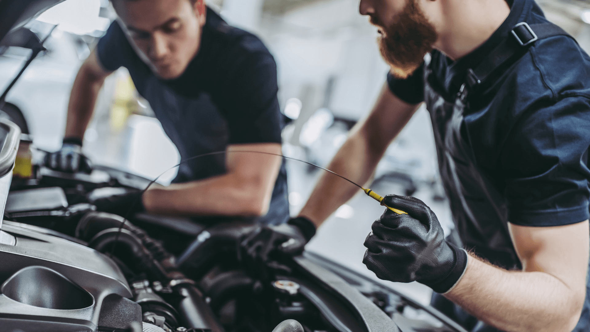 Deux mécaniciens inspectant un moteur de voiture dans un atelier.